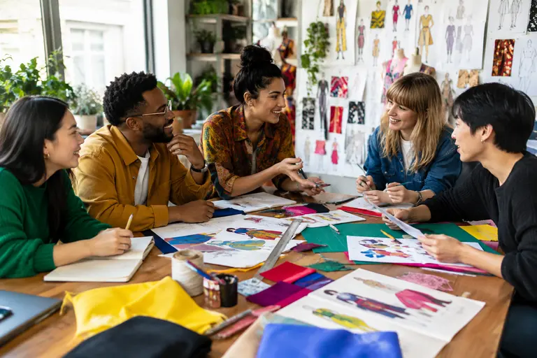 Sewing tools, paper pattern pieces, and a half-scale cape mockup on a table